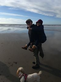 Full length of friends on beach against sky