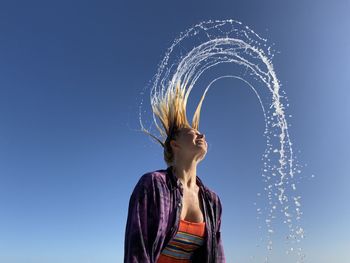 Low angle view of woman looking at blue sky