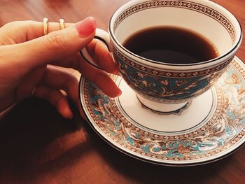 Close-up of woman holding coffee cup on table
