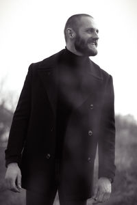 Close-up of man looking away while standing against sky