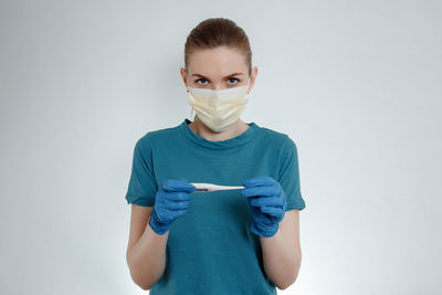 Portrait of young woman standing against white background