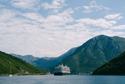 Boat sailing on sea by mountains against sky