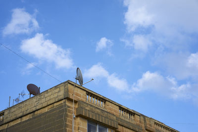 Low angle view of bird perching on building against sky