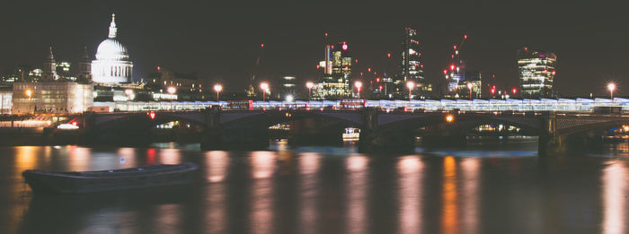 Illuminated bridge over river at night