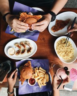 Cropped hands of friends having food at table