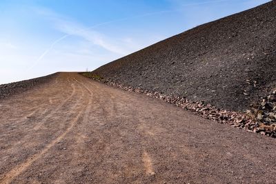 Road amidst land against sky