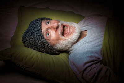 Shocked senior man with mouth open lying on bed at home