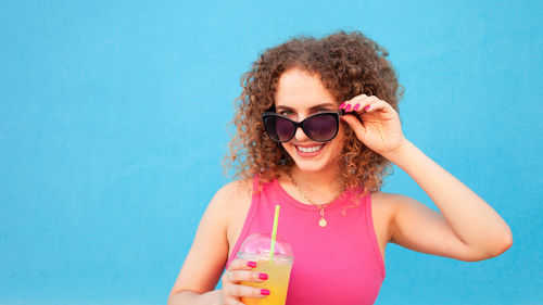 Beautiful happy woman with orange cold juice, concept summer drinks, rest and vacation. blue