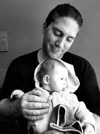 Father looking at daughter while sitting against wall at home