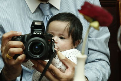 Man with camera carrying baby while sitting on sofa