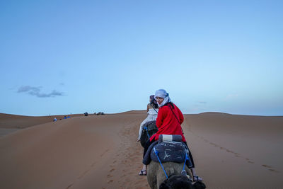 Rear view of man on desert against sky