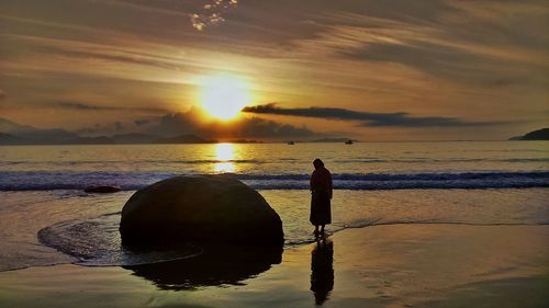 Man on beach against sky during sunset