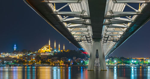 Illuminated bridge over river in city at night