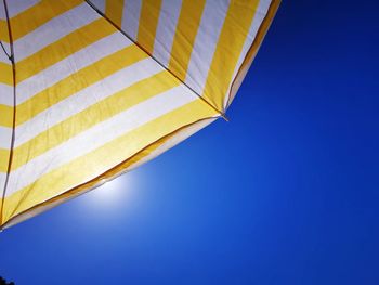 Low angle view of yellow flag against clear blue sky