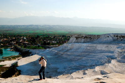 Rear view of man standing on rock against sky