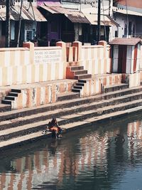 Reflection of people on building by canal