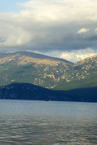 Scenic view of sea and mountains against cloudy sky