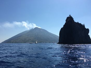 Scenic view of sea and mountains against blue sky
