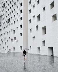 Rear view of people walking by building in city