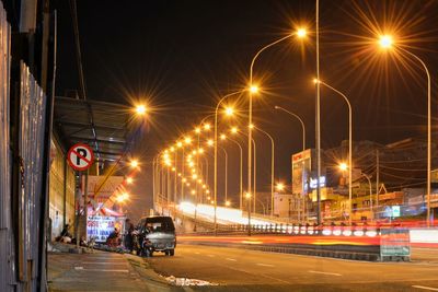 Cars on illuminated road against sky at night