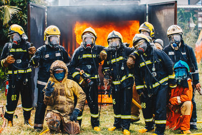 Portrait of firefighters standing on field 