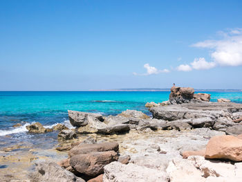 Rocks on beach against blue sky