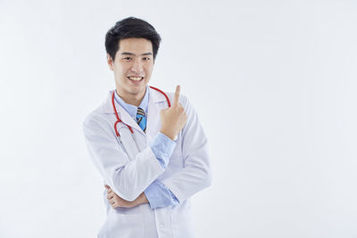 Portrait of smiling young man standing against white background