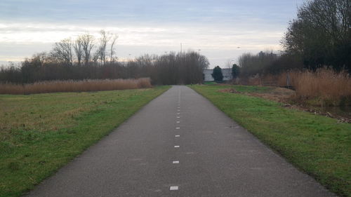 Road amidst field against sky