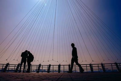 Silhouette people on beach against clear sky during sunset