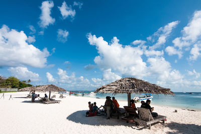 People relaxing at beach against blue sky