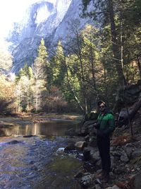 Portrait of young man standing on rock in forest