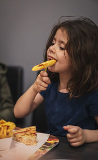 Little girl eats french fries in a cafe.