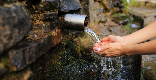 Cropped hand of woman cleaning hands at water