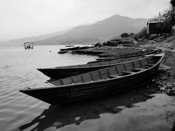 Boat moored on lake against sky