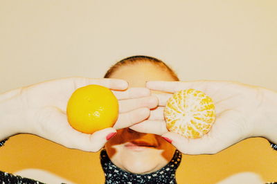 Close-up of hand holding oranges over eyes