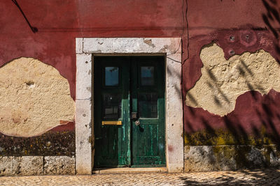 Closed door of old house in lisbon. the wall is deteriorated by rising damp and peeling plaster.