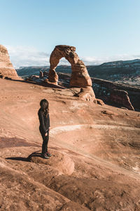 Woman standing on rock against sky