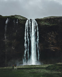 Friends standing against waterfall