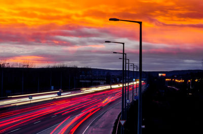 Light trails on road against sky during sunset