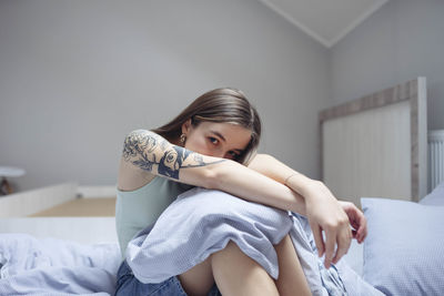 Woman sitting on bed arms outstretched