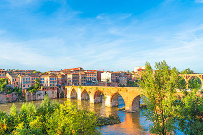 Arch bridge over river against blue sky