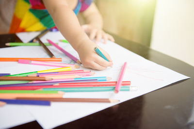 Midsection of boy holding book with text on table