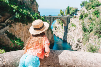 Rear view of woman with hat on bridge over river