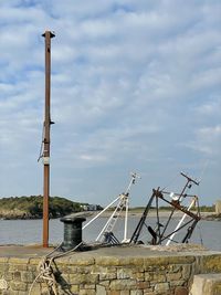 Metallic structure on beach against sky