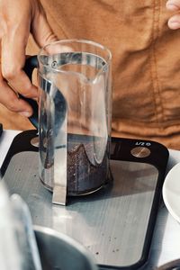 Midsection of man holding coffee cup on table