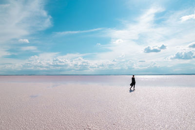 Woman at beach against sky during sunny day