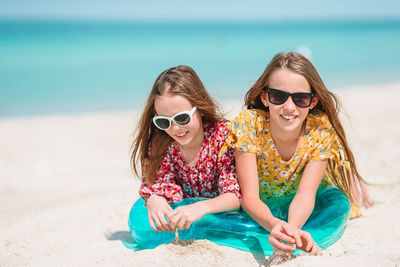 Portrait of sisters sitting on beach