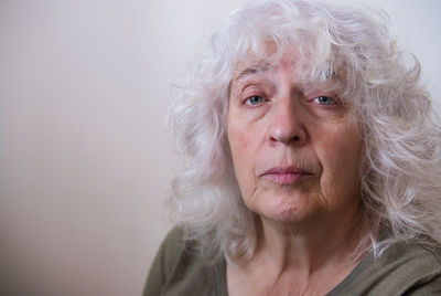 Portrait of an elderly gray-haired curly lady with long hair.