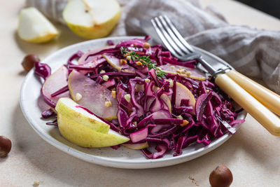 Red cabbage, pear and hazelnut salad with lemon and olive oil sauce. vegetarian food. 