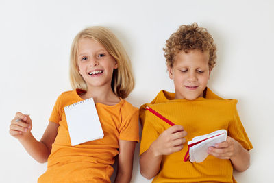 Portrait of smiling girl lying on white background with brother